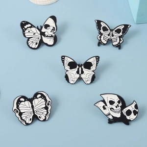Detailed flat lay of five punk style skull butterfly enamel pins on a blue background