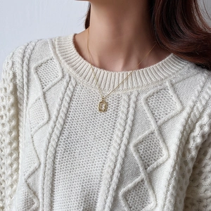 Irregular textured gold geometric pendant necklace styled on a white knit sweater