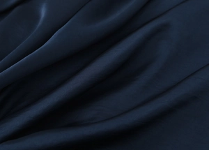 Nahaufnahme von dunkelblauem Satinstoff mit elegantem Seidenglanz und weichem Faltenwurf