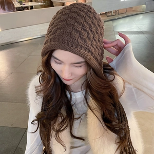 Detail of chunky knit brown beanie with long braided tassels in cozy winter style