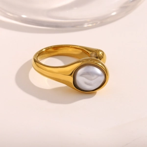 Macro view of gold-plated snake head ring with round pearl inlay on thick metal band