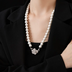 Detail of silver flower clasp and synthetic pearls on necklace worn by model