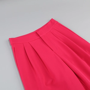 Detail of rose red high-waisted wide-leg trousers with front pleats and zipper fly