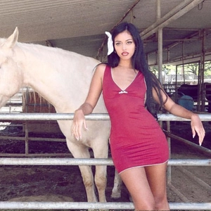 Outdoor shot of red V-neck mini dress with white trim and bow detail on a model