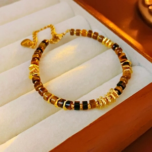 Detailed macro view of brown tiger eye beads and gold clasp on a velvet jewelry tray