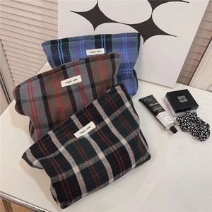 Detailed view of plaid cotton makeup bags in blue-green, gray-red, and black-white grids