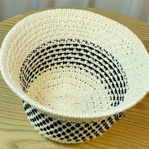 Detail view of woven straw bucket hat with beige and black geometric patterns on wood