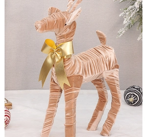 Detail of champagne velvet reindeer ornament with gold bow and elegant wrinkled texture