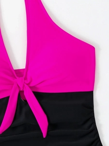 Detail of color block halter swimsuit with fuchsia top, black bottom and front knot