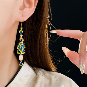 Dettaglio di orecchini a pavone placcati oro 14K con petali in smalto su modella