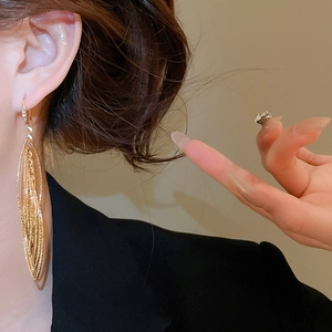 Gros plan de boucles d'oreilles pendantes dorées à pampilles multicouches