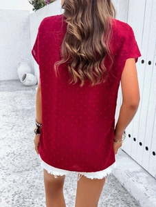 Rear view of women's red short-sleeved V-neck blouse featuring a delicate polka dot pattern
