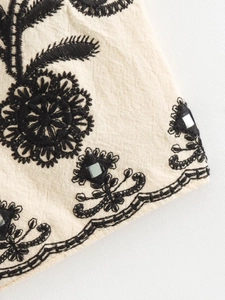 Detail of floral black embroidery and mirror work on beige cotton linen fabric