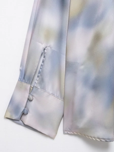 Detailed view of tie-dye satin shirt cuffs featuring fabric-covered double buttons