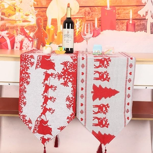Detailed knitted Christmas table runner with reindeer motifs and festive red tassels