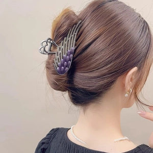 Detailed view of silver angel wing hair claw clip with purple rhinestones on a bun