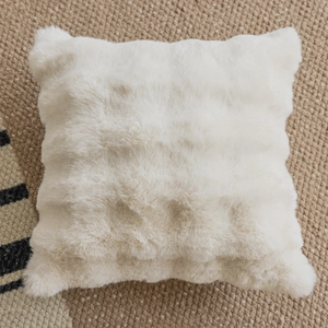 Minimalist white faux fur square pillow cover on a textured woven rug for home decor