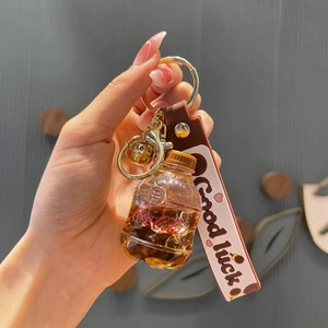 Creatieve frisdrankfles sleutelhanger met bruine vloeistof, belletje en roze riem