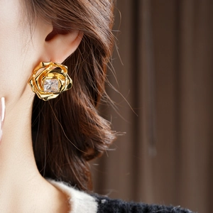 Gros plan d'une boucle d'oreille fleur plaquée or 18k avec cristal carré sur modèle