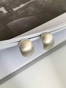 Detail of matte silver geometric earrings with brushed finish on magazine edge