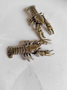 Detailed macro shot of two antique brass lobster figurines with realistic shell textures
