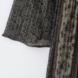 Détail du motif floral vintage sur tissu transparent avec des rayures dorées verticales