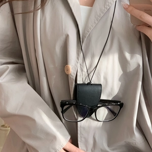 Close-up of black leather glasses pouch necklace with sunglasses worn over a beige shirt