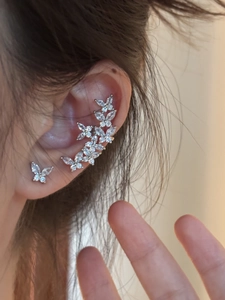 Close-up of elegant silver butterfly ear cuff with micro-paved zircons worn on the ear