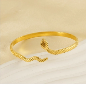 Macro detail of 18k gold snake-shaped bangle showing textured mesh scale patterns