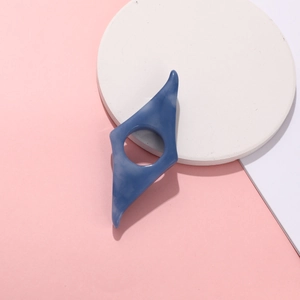 Macro detail of a blue resin thumb book page holder on a minimalist geometric pink background