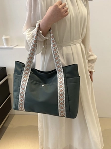 Dettaglio della borsa tote verde scuro con tracolla etnica e vista della tasca laterale