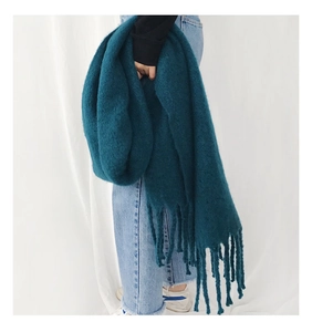 Detailed view of the peacock blue thick knit scarf with soft cashmere-like fringe texture