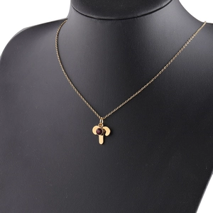 Detail of a gold zodiac necklace with red birthstone pendant on a black bust