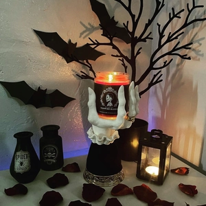 Macro detail of white witch hand candle holder with gold rings and red vampire candle