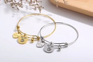 Detail of adjustable heart bracelets with Love charm and girl pendant in gold and silver