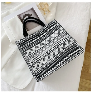 Detail of woven tote bag featuring black and white geometric patterns and sturdy handles