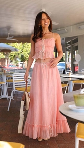 Detail of pink pleated two-piece set featuring camisole top and maxi skirt on model
