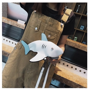Close-up of a white leather shark-shaped crossbody bag with blue fins and metal hardware