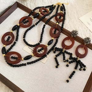 Detail of bohemian layered necklace and crystal earrings with coffee resin rings