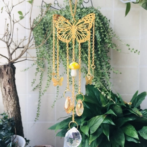 Detail of golden butterfly suncatcher with yellow mushroom and faceted crystal pendant