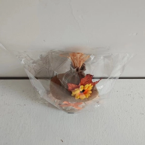 Macro view of autumn burlap mini hat with maple leaves and pumpkin bow in clear bag