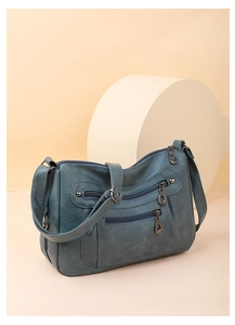 Detail of dark teal faux leather bag with multiple zippers and vintage metal hardware