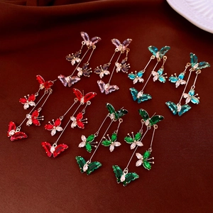 Detailed view of colorful butterfly tassel earrings with zircon insets on velvet