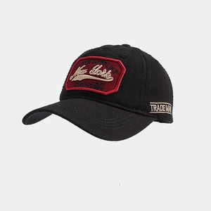 Detailed view of red embroidery patch and white side lettering on a black cotton baseball cap