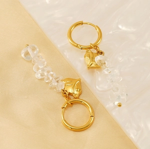 Detail of golden fox earrings with hanging natural stones and round hoops on silk fabric