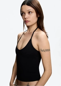 Side view of a black halter neck backless crop top highlighting its slim fit and sleek profile