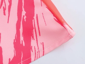 Detailed close-up of pink tie-dye print fabric and precise stitching on the dress hemline