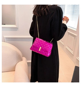 Detail of quilted fuchsia chain bag with metallic finish and gold rectangular clasp