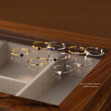 Close-up of S925 silver heart rings in gold and silver finish on a wooden box