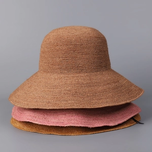 Three stacked wide brim raffia sun hats in brown pink and gold colors for summer wear